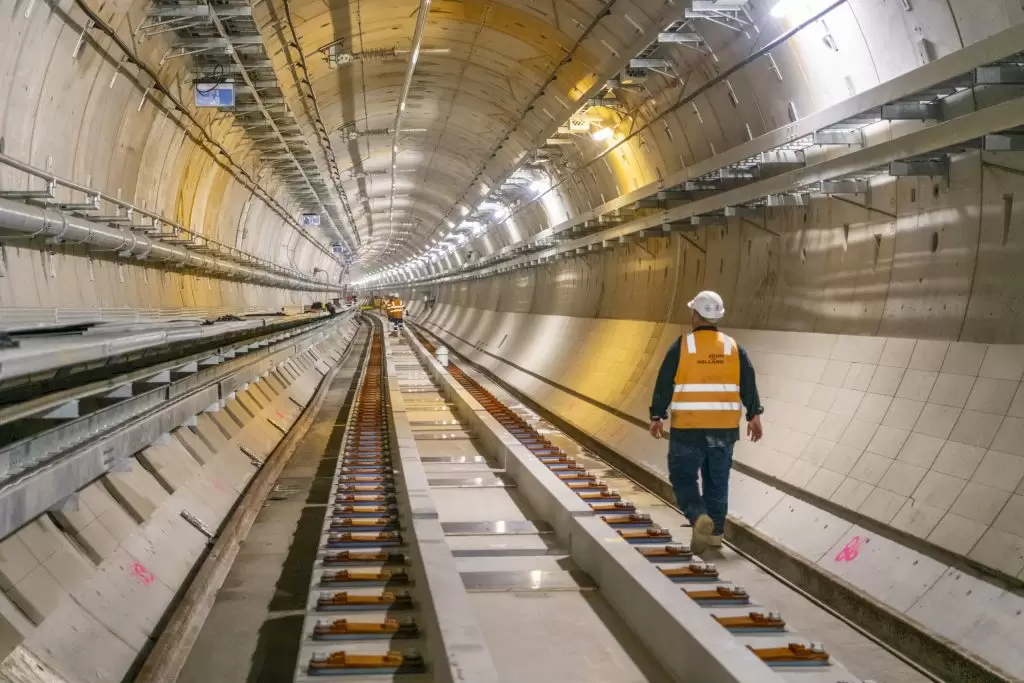 Worker in hi-vis walking a rail tunnel under construction